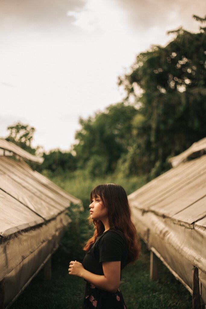 a woman in black top standing between greenhouses