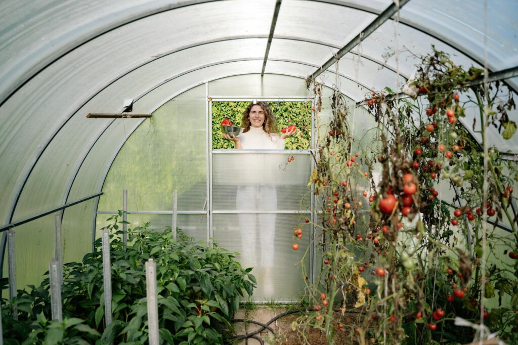 woman standing behind window of greenhouse