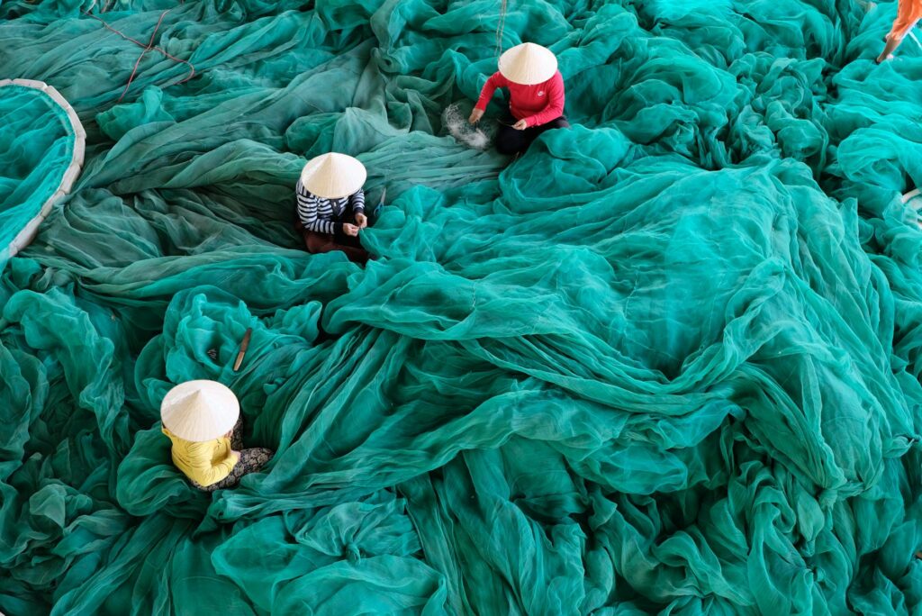 three person sitting on green large net